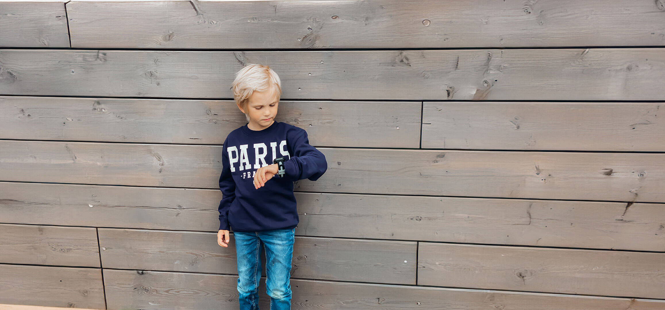 Liten blond kille med mobil klockan.