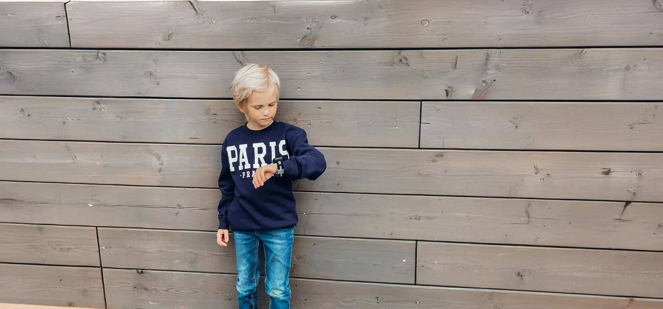 Liten blond kille med mobilklockan.